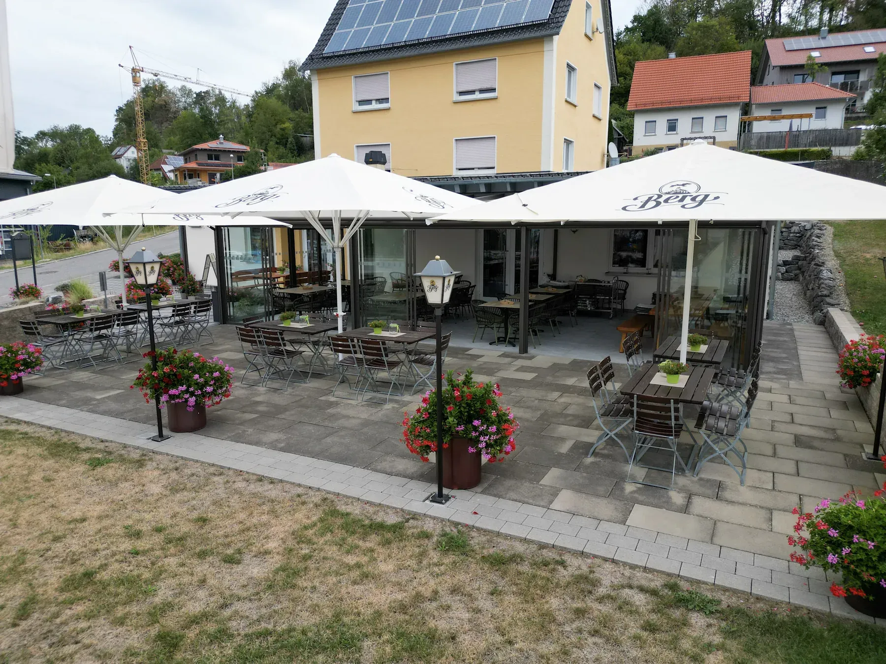 Terrasse des Gasthaus Löwen mit Sonnenschirmen, Blumen und Blick auf das Gasthaus