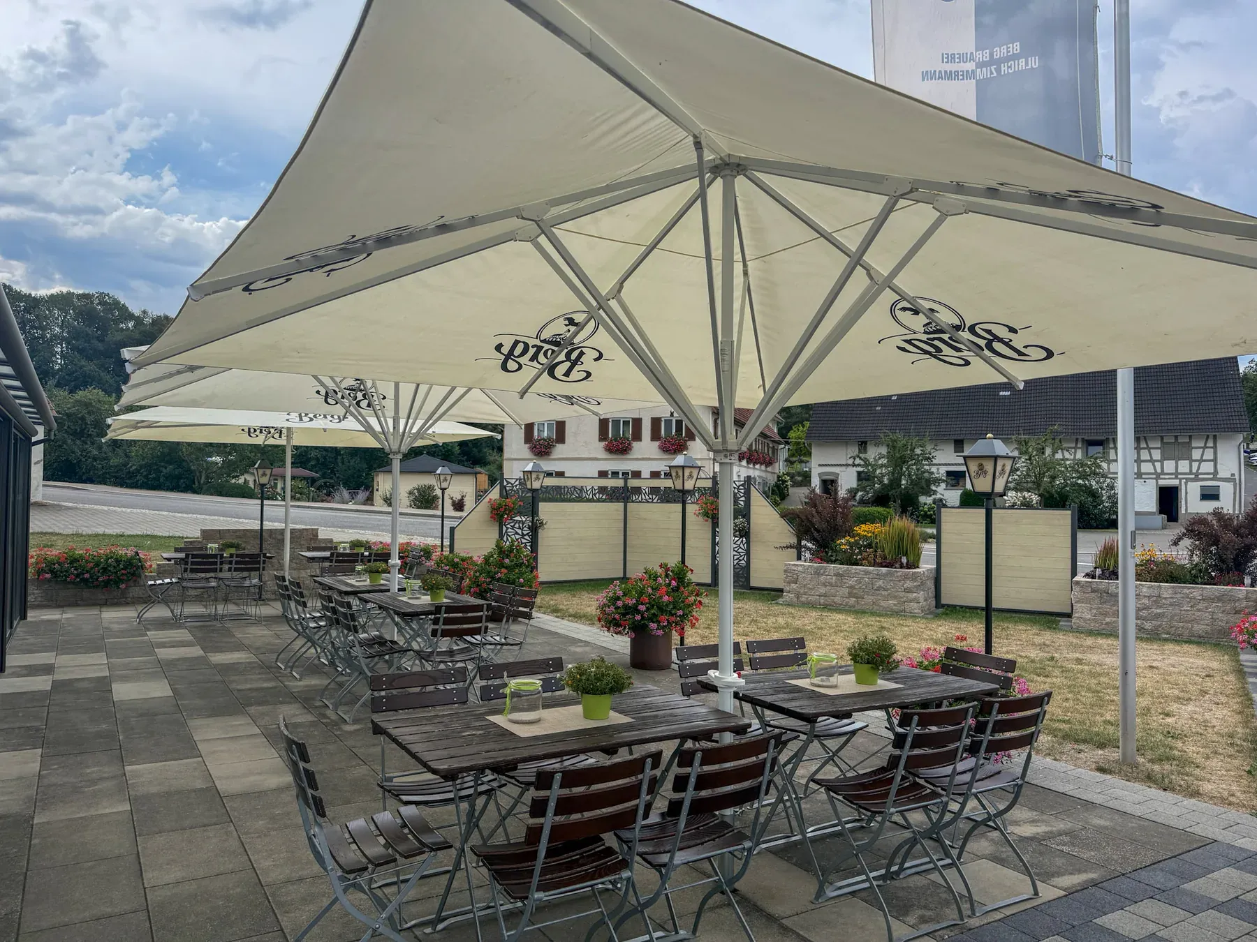 Terrasse des Gasthaus Löwen unter großen Sonnenschirmen mit Blick ins Dorf Rottum