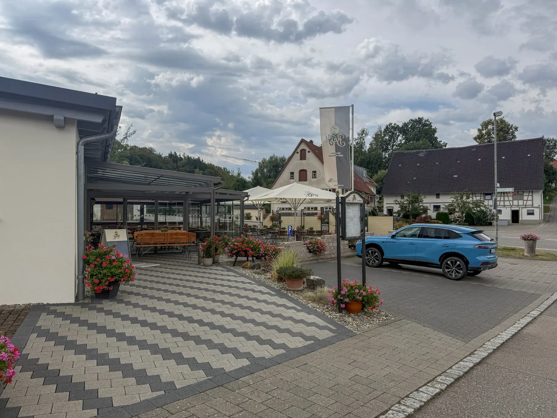 Eingang des Gasthaus Löwen mit überdachtem Vorplatz, Blumen und Parkplatz direkt am Haus